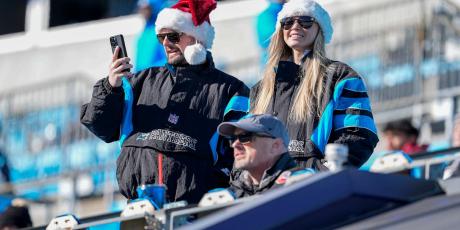 Fan checking the waiver wire in a christmas hat in stands 